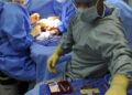 Équipe de chirurgiens en tenue opératoire penchée sur un patient au bloc