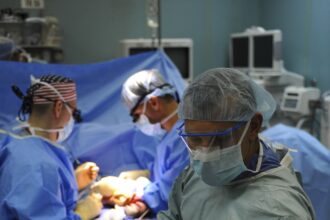 Équipe de chirurgiens en tenue opératoire penchée sur un patient au bloc