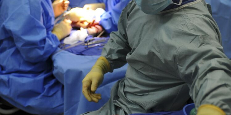 Équipe de chirurgiens en tenue opératoire penchée sur un patient au bloc