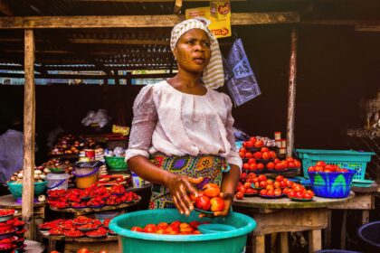 Une vendeuse présente des tomates fraîches sur un étal de marché en plein air