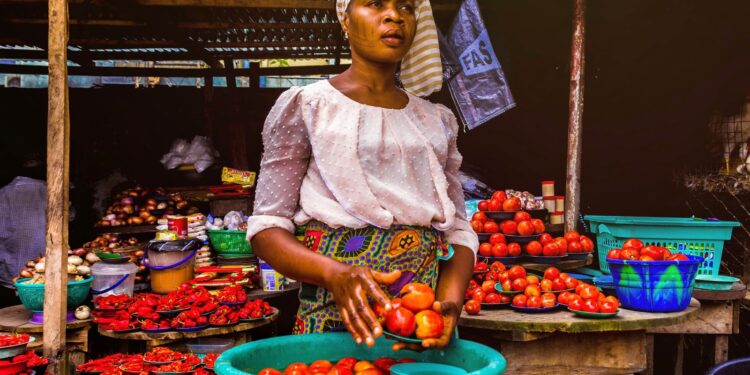 Une vendeuse présente des tomates fraîches sur un étal de marché en plein air